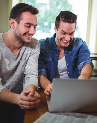 happy-friends-laughing-while-looking-laptop-cafe